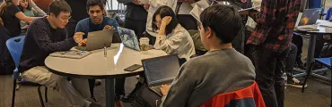 group of students with laptops working at a table