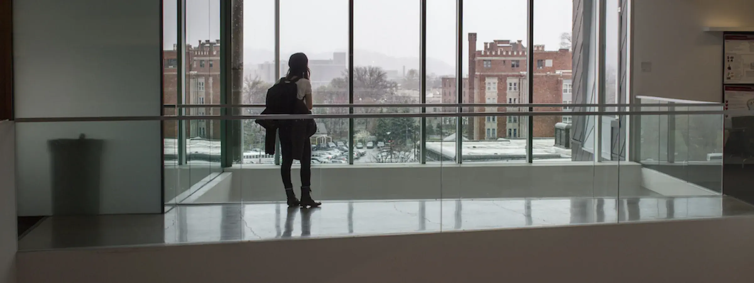 Student standing in front of a large window in the Gates Center at Carnegie Mellon University